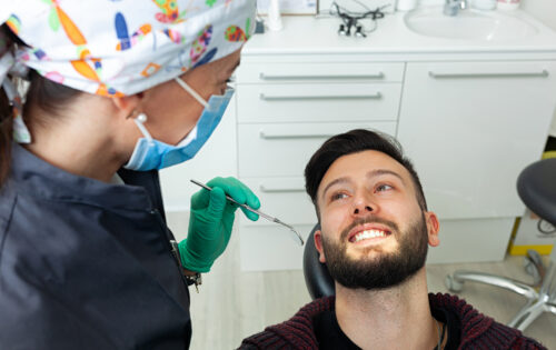 Man in a dental chair talks to dentist about symptoms of wisdom teeth coming in
